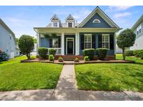Charming blue home featuring manicured lawn and walkway, black shutters, and a welcoming front porch at 17711 North Shore Cir, Cornelius, NC 28031