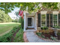Charming front entrance with stone accents, American flag, and beautifully landscaped yard at 18439 Victoria Bay Dr, Cornelius, NC 28031