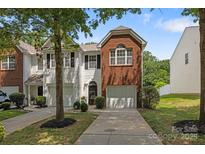 Charming townhome featuring an attached garage, brick facade, and landscaped front yard at 2137 Whispering Way, Charlotte, NC 28212
