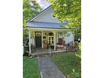 Charming cottage-style home with a quaint front porch decorated with flowers and vintage decor at 215 9Th St, Spencer, NC 28159