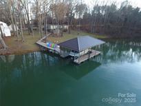 Beautiful lakefront home featuring a covered boat dock, lakeside seating area and mature trees at 2721 Nance Cove Rd, Charlotte, NC 28214