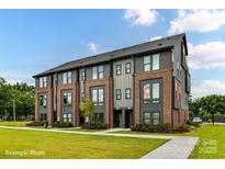 Modern townhome with brick and gray siding, sidewalk, and lush green lawn at 3006 Khan Park Dr # 69, Charlotte, NC 28206