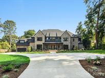Stunning brick home featuring manicured lawns, a circular driveway, and classic architectural details at 5311 Carmel Park Dr, Charlotte, NC 28211