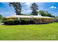 Charming brick home with a well-manicured lawn, lush greenery, and a welcoming front porch at 938 Kannapolis Pkwy, Concord, NC 28027