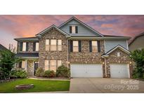 Beautiful two-story brick home featuring a two-car garage and manicured lawn with an inviting sunset in the background at 1281 Arges River Dr, Fort Mill, SC 29715