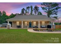 Charming brick home featuring a welcoming front porch, manicured lawn, and inviting landscaping at 1916 Bess Town Rd, Bessemer City, NC 28016