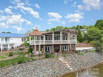 Beautiful waterfront home featuring a spacious porch, well-maintained landscaping, and a charming, copper-roofed turret at 216 Grand View Dr, New London, NC 28127