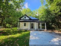 Charming renovated home with a welcoming front porch, set amidst a lush green lawn and mature trees at 409 Everette St, Monroe, NC 28112