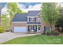 Charming two-story brick home featuring a well-manicured lawn and inviting front porch at 111 Painted Bunting Dr, Troutman, NC 28166