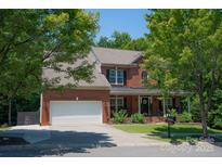 Charming red brick home with a covered front porch, white garage door, and mature trees at 1125 Victoria Blake Ln, Belmont, NC 28012