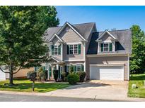 Charming two-story home with a well-manicured lawn, green shutters, and a two-car garage on a sunny day at 119 Tilton Dr, Mooresville, NC 28115