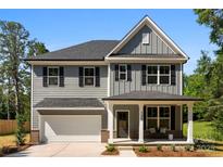 Charming two-story home with gray siding, black shutters, covered front porch, and attached two-car garage at 1227 Breezewood Dr, Charlotte, NC 28262