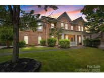 Charming brick home featuring manicured lawn, lush landscaping, and a welcoming front porch at 125 Snow Fountain Ln, Mooresville, NC 28115