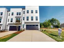 Modern townhouse with a dark garage door, concrete driveway, and well-maintained landscaping at 2143 Barrowcliffe Nw Dr, Concord, NC 28027