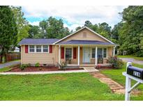 Charming single story home featuring a cozy front porch with rocking chairs and a well-maintained lawn at 218 Blacksnake Rd, Stanley, NC 28164