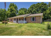 Charming brick home featuring a welcoming front porch and lush green lawn at 2526 Ashford Dr, Newton, NC 28658