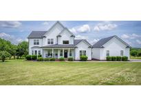 Charming two-story home with a covered front porch, manicured lawn, and lush landscaping at 594 Patterson Farm Rd, Mooresville, NC 28115