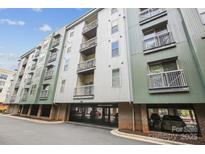 View of a modern apartment building with balconies and gated parking against a blue sky at 630 Calvert St # 410, Charlotte, NC 28208