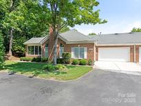 Charming brick home with a well-maintained lawn, mature tree, and an attached two-car garage at 8465 Olde Troon Dr, Charlotte, NC 28277