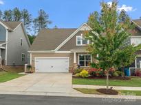 Charming home featuring a two-car garage, manicured lawn, and colorful flowerbeds at 1008 Whipcord Dr, Waxhaw, NC 28173