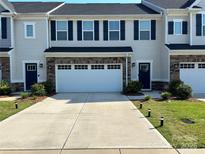 Beautiful townhome with a two car garage, stone accents, a concrete driveway, and well manicured landscaping at 10412 Dalton Woods Nw Ct, Huntersville, NC 28078