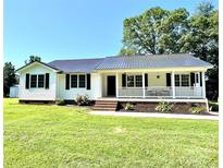 Charming one-story home featuring a welcoming front porch, green lawn and a durable metal roof at 147 Dutchman Rd, Harmony, NC 28634