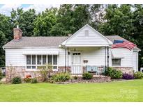 Charming single-story home with a brick foundation, quaint porch, and well-manicured lawn and an American Flag at 409 E 18Th St, Kannapolis, NC 28083