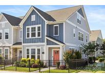 Charming two-story home featuring a black metal fence, blue siding, and a vibrant coral front door at 5008 Calvine Mill Way, Charlotte, NC 28205