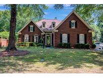 Charming brick home with manicured lawn, black shutters, and lush landscaping exudes curb appeal at 7014 Walton Heath Ln, Charlotte, NC 28277