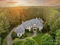Stunning aerial view of a luxury home with a meticulously landscaped yard surrounded by lush greenery at 9110 Woodhall Lake Dr, Waxhaw, NC 28173