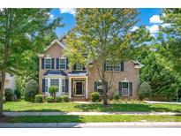 Charming brick two-story home with manicured lawn, mature trees, and dark shutters at 10104 Treetop Ln, Cornelius, NC 28031