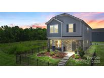 Charming home featuring stone accents, inviting front porch, landscaped yard, and a decorative black metal fence at 135 Orson Oaks Ln, Pineville, NC 28134