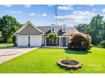 Charming single Gathering home featuring a two-car garage and manicured lawn with flowering shrubbery and a proud American flag at 181 Brook Glen Dr # 56, Mooresville, NC 28115