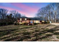 Charming brick home featuring manicured landscaping and a well-maintained lawn during a beautiful sunset at 220 Augusta Dr, Statesville, NC 28625