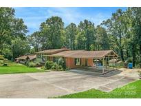 Ranch-style home featuring a covered parking area and a swimming pool surrounded by mature trees and landscaped grounds at 408 E Blume St, Landis, NC 28088