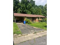 Cozy single-story brick home featuring a carport and a driveway surrounded by lush greenery and mature trees at 413 Mclelland Ave, Mooresville, NC 28115