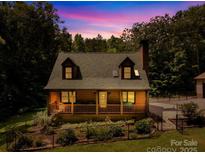 Charming cabin with a covered front porch and dormer windows against a colorful sunset backdrop at 485 Johnson St, China Grove, NC 28023