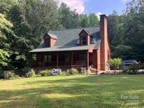 Charming log cabin with a brick chimney, dormer windows, a covered porch, and a well-manicured front lawn at 485 Johnson St, China Grove, NC 28023