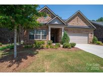 Charming brick home featuring a well-manicured lawn, flower beds, and an attached two-car garage at 5268 Courtyard Ln, Belmont, NC 28012