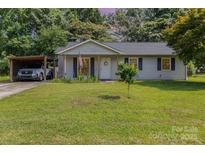 Charming single-story home with well-maintained lawn, carport and patriotic curb appeal at 7224 Newell Acres Dr, Charlotte, NC 28215