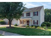 Charming two-story home features a well-manicured lawn, mature tree, and red shutters that add a pop of color at 9410 Culcairn Rd, Huntersville, NC 28078