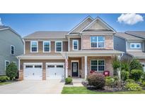Charming two-story home featuring a brick and brown siding, a two-car garage and an inviting front porch at 134 Cherry Bark Dr, Mooresville, NC 28117