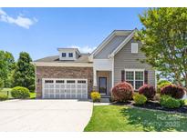 Charming home featuring a stone facade, a two-car garage and a well-manicured front lawn and landscaping at 159 E Warfield Dr, Mooresville, NC 28115