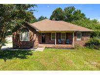 Charming brick ranch-style home featuring a well-manicured lawn and inviting front porch with seating at 160 Walking Horse Run, Stanley, NC 28164