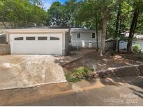 Charming one-story home featuring a detached garage, walkway, and inviting front yard, nestled amongst mature trees at 27 Quayside Ct, Clover, SC 29710