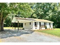Charming single-story home with a carport, featuring a brick facade and complemented by mature trees at 617 Rock Hill Church Rd, Matthews, NC 28104