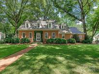 Charming brick home with mature trees, dormer windows, and lush green lawn at 827 Museum Dr, Charlotte, NC 28207