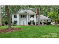 Classic colonial-style home with a manicured lawn, mature trees, and symmetrical facade at 9424 Whitethorn Dr, Charlotte, NC 28277