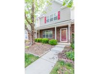 Charming townhouse featuring a brick facade, red shutters, and a well-maintained front yard with mature trees and walkway at 10763 Holly Ridge Blvd, Charlotte, NC 28216