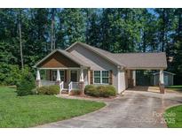 Charming single-Gathering home with covered porch, carport, and well-manicured lawn surrounded by lush greenery at 110 Leeper Ave, Belmont, NC 28012